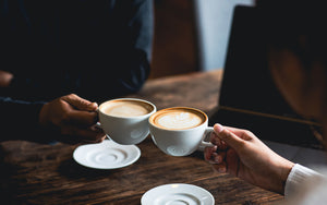 Two people toast with cafe lattes