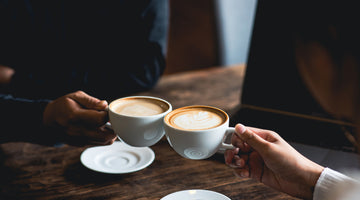 Two people toast with cafe lattes
