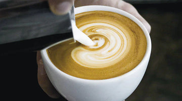 milk being poured into a cappuccino