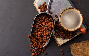 Coffee Beans in a scoop with a cup of coffee