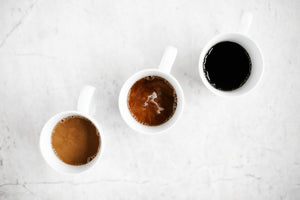 different types of coffee in white mugs from dark to light
