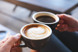 Hands holding two espresso drinks