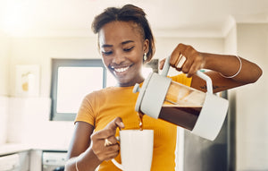 woman pours a cup of french press coffee